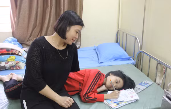 Chị Thanh Hằng ngắm con gái Minh Thư vẽ tranh trên giường bệnh.