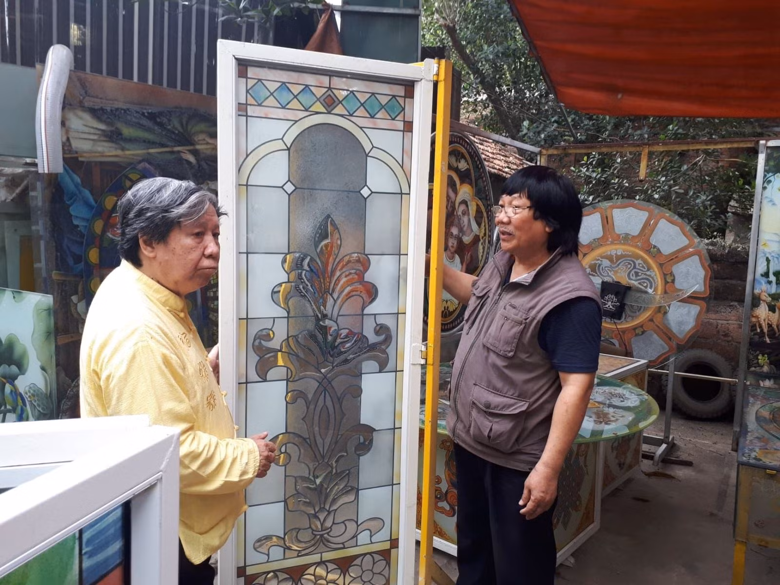 Ông Phạm Hồng Vinh (bên phải) đang giới thiệu nghệ thuật làm tranh kính.