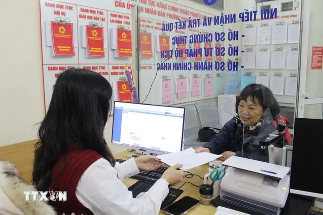 Cán bộ phường hướng dẫn người dân làm thủ tục hành chính. (Ảnh: Nguyễn Thắng/TTXVN)