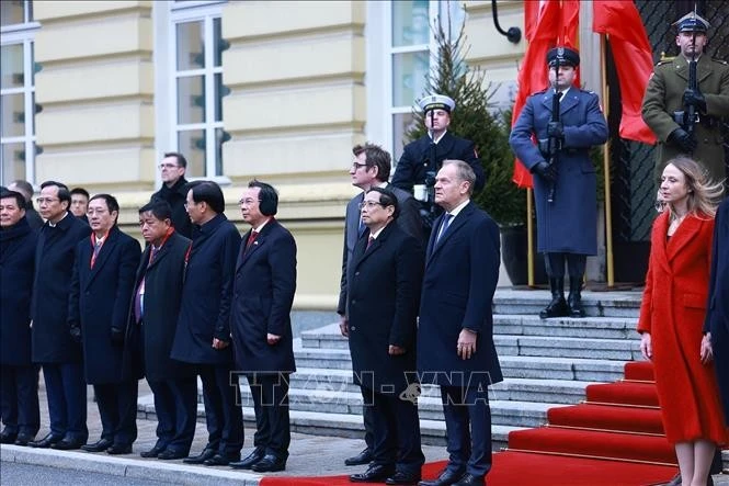 Thủ tướng Phạm Minh Chính và Thủ tướng Cộng hòa Ba Lan Donald Tusk nghe quân nhạc cử Quốc thiều hai nước. Ảnh: Dương Giang/TTXVN