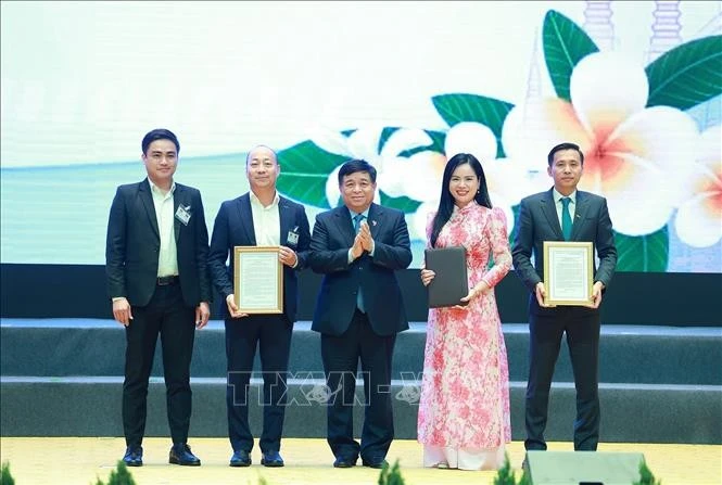 Bộ trưởng Bộ Kế hoạch và Đầu tư Nguyễn Chí Dũng trao chứng nhận đăng ký và thoả thuận đầu tư cho các doanh nghiệp Việt Nam có hợp tác với Lào. Ảnh: Dương Giang/TTXVN
