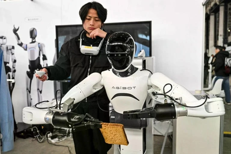 Một người đàn ông điều khiển robot Agibot. Ảnh: AFP
