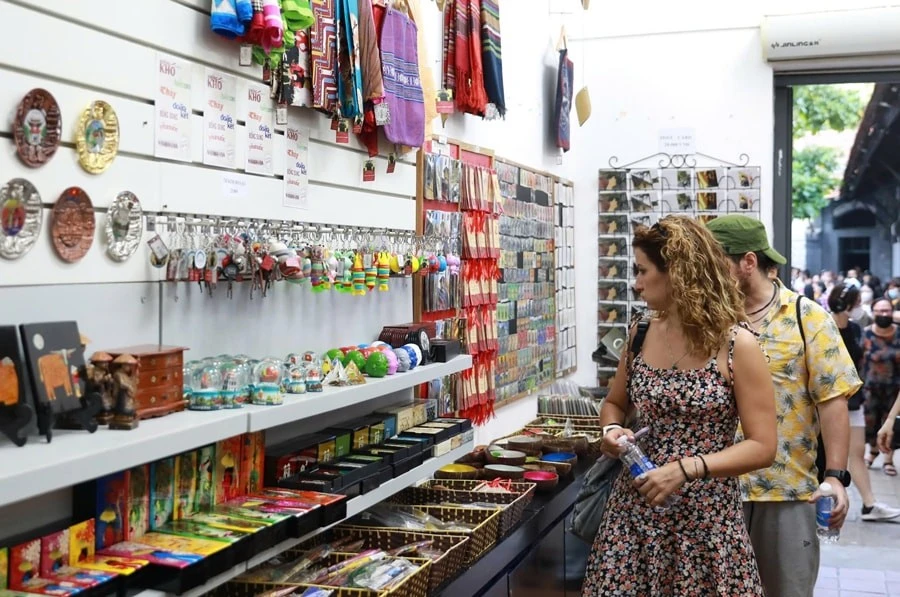 Du khách quốc tế lựa chọn các sản phẩm quà tặng du lịch tại Di tích Nhà tù Hỏa Lò. Ảnh: Đỗ Tâm