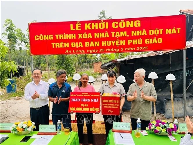 Bí thư Tỉnh ủy Bình Dương Nguyễn Văn Lợi (phải) trao suất xóa nhà tạm cho hộ bà Nguyễn Thị Gái, xã An Long, huyện Phú Giáo. Ảnh: TTXVN phát