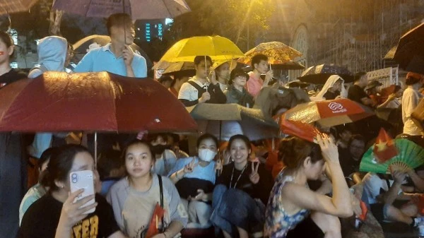 Người dân đứng dưới mưa kiên nhẫn chờ đến giờ xem diễu binh.