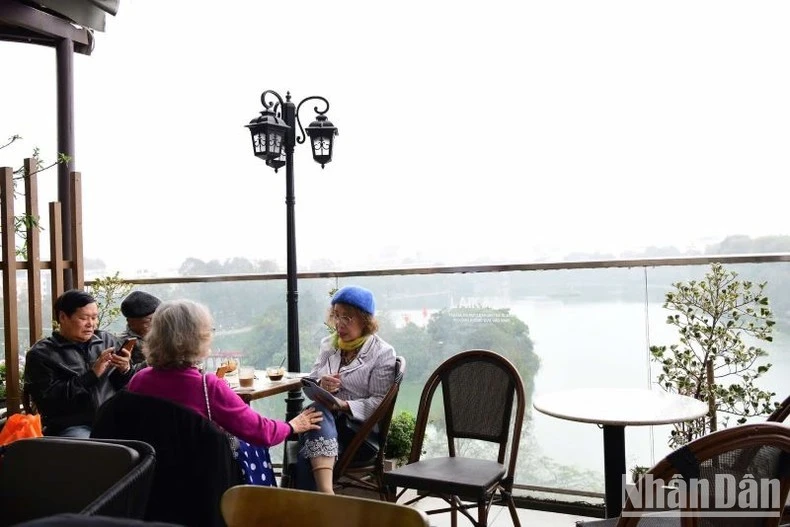 Người dân chọn vị trí ngồi trên cao từ tòa nhà thưởng thức cảnh đẹp Hồ Gươm trọn tầm mắt. (Ảnh: Thế Dương)