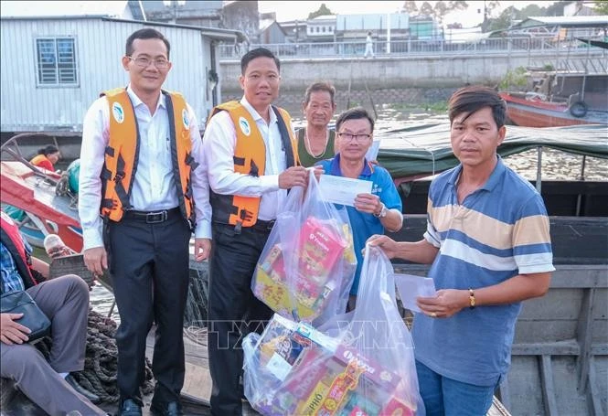 Phó Chủ tịch UBND thành phố Cần Thơ Nguyễn Thực Hiện (thứ hai, bên trái) trao quà Tết cho tiểu thương Chợ nổi Cái Răng. Ảnh: Thanh Liêm - TTXVN