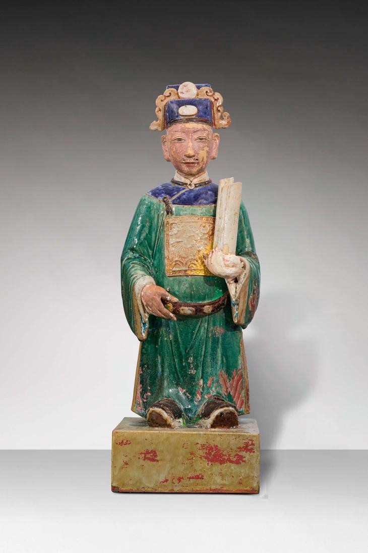 Tượng thị giả (người hầu) đứng trên bệ hình vuông, đầu đội mũ phốc vuông đắp nổi viên ngọc và mây. Mặt để mộc, dùng sơn để vẽ chân mày và mắt, tai to, trên mặt tạo 5 lỗ để gắn râu. Thân mặc áo dài màu xanh lá, phần vai áo màu xanh lam viền nâu, có đai, trên thân áo có bổ tử trang trí hình chim phượng, thủy ba, mây đối xứng trước và sau lưng. Tay trái cầm quyển sổ, một đầu gác trên vai trái, tay phải cầm đai, chân mang hia.