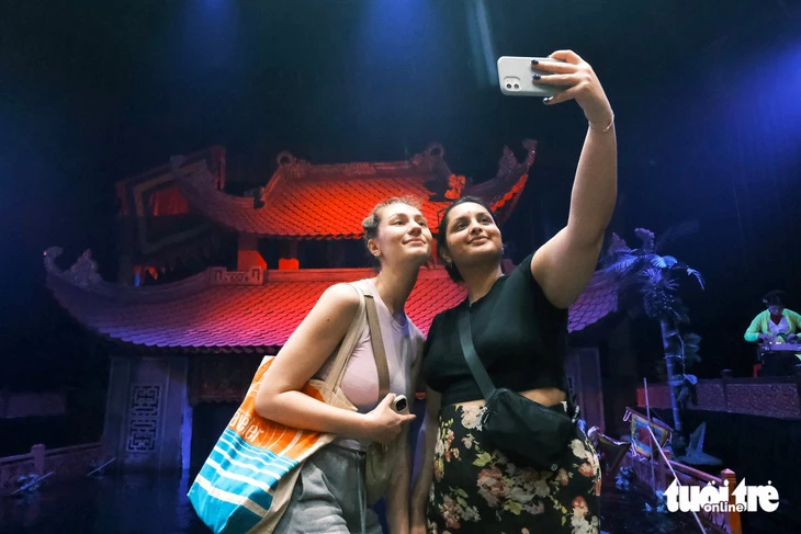 Du khách nước ngoài chụp ảnh khi đi xem múa rối nước ở Hà Nội.