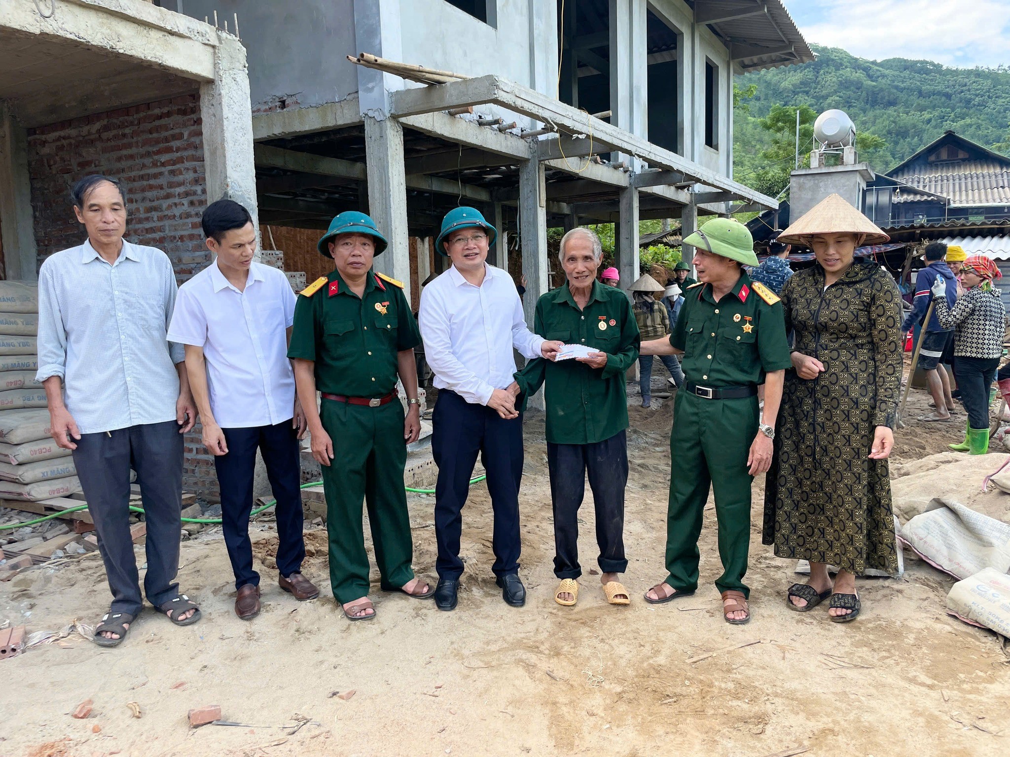 Chủ tịch Ủy ban Mặt trận Tổ quốc Việt Nam phường Nghĩa Lộ (áo trắng đội mũ cối) trao tiền hỗ trợ cho hội viên cựu chiến binh khó khăn làm nhà ở. 21.jpg