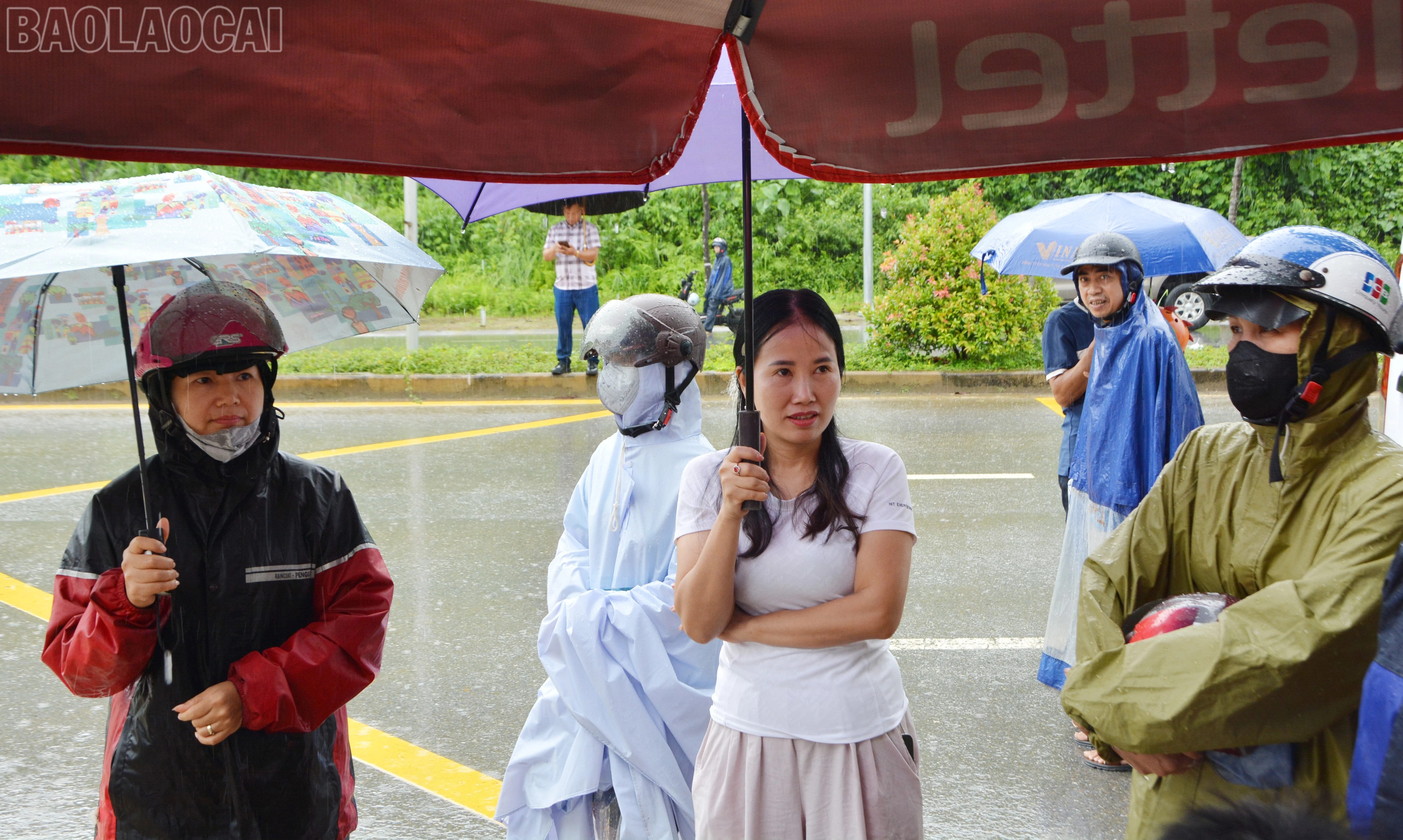 Sau khi đưa thí sinh đến điểm thi an toàn, nhiều phụ huynh đội mưa, nán lại phía ngoài khu vực thi để đợi thí sinh.
