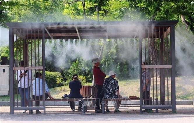 Người dân tránh nóng bên dưới hệ thống phun sương tại một công viên ở Seoul, Hàn Quốc. 15-7-nang-nong-hq-1880.jpg
