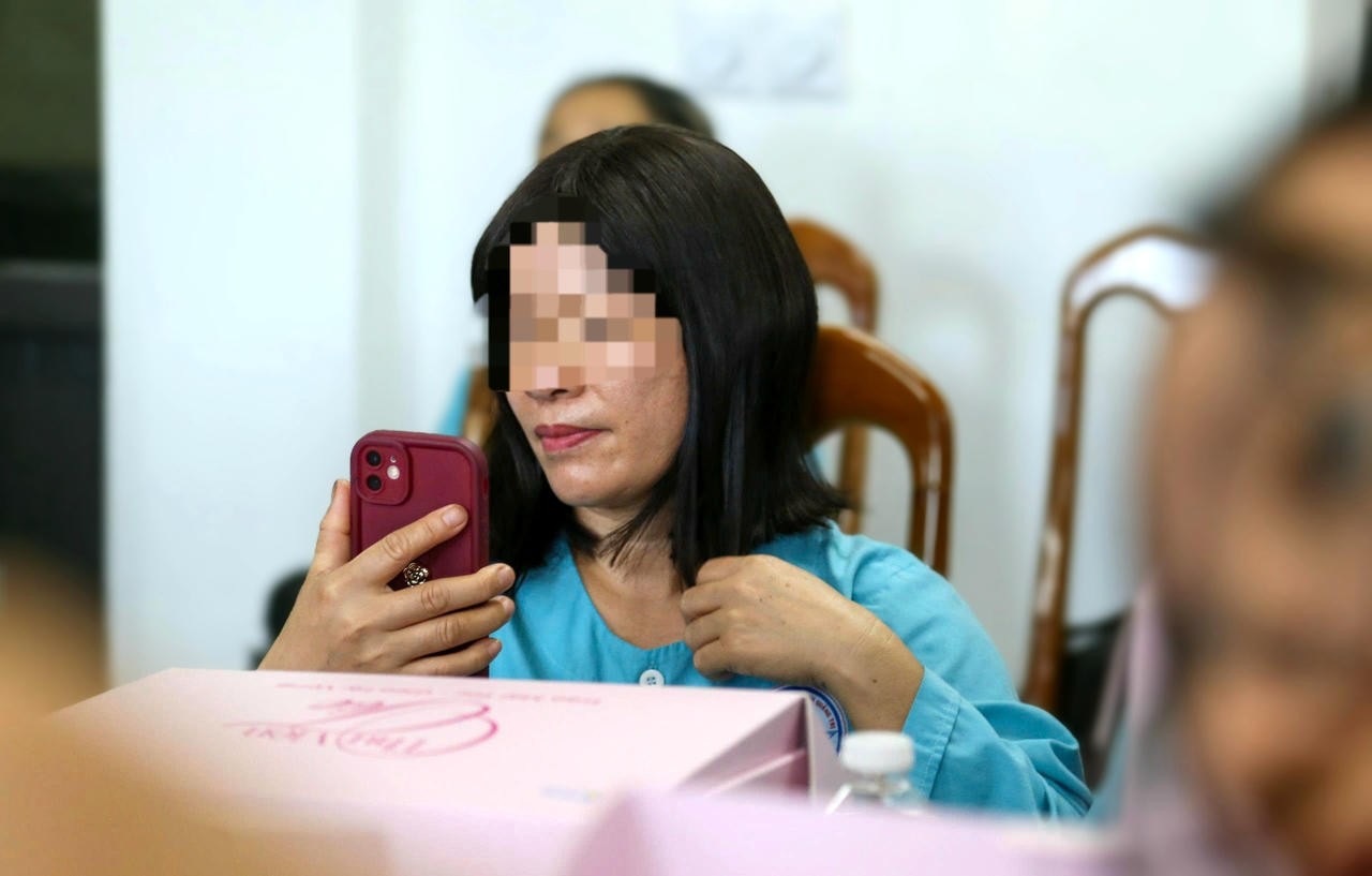 Bà N. đưa điện thoại lên soi, ngắm nghía bản thân với bộ tóc mới được trao tặng. Bà N. đưa điện thoại lên soi, ngắm nghía bản thân với bộ tóc mới được trao tặng.