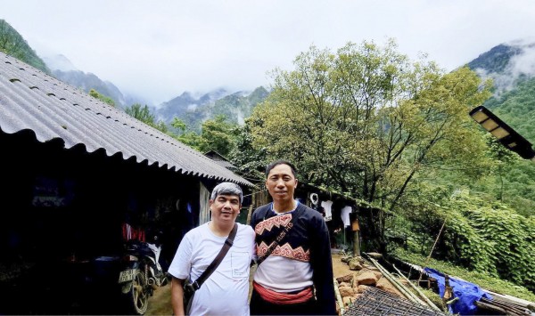 អ្នកនិពន្ធ និងមេភូមិ Vang A Chinh នៅជាប់ផ្ទះនៅភូមិ Sin Suoi Ho។ Tác giả và Trưởng bản Vàng A Chỉnh bên ngôi nhà ở bản Sin Suối Hồ.