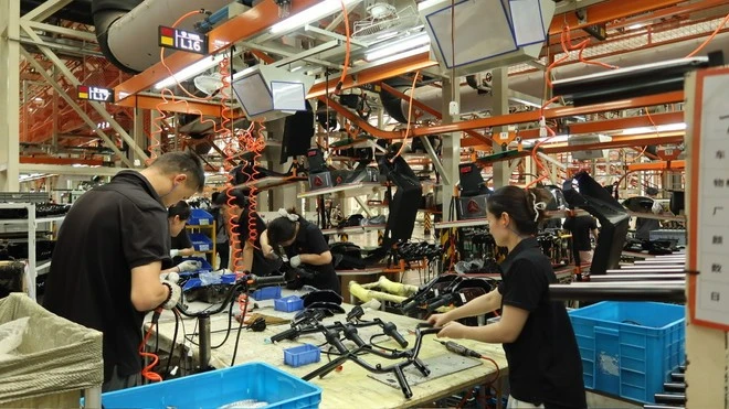 Công nhân nhà máy sản xuất xe điện Yadea làm việc hăng say bên các máy móc được trang bị hiện đại.