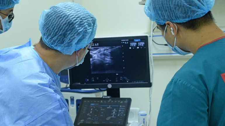 Dưới hướng dẫn siêu âm, ê-kíp bác sĩ Bệnh viện Nội tiết Trung ương đã sử dụng đầu kim đốt chuyên dụng tiếp cận chính xác khối hạch, áp dụng kỹ thuật moving-shot và bơm dịch ngăn cách nhằm bảo vệ các mạch máu lớn xung quanh. Dưới hướng dẫn siêu âm, ê-kíp bác sĩ Bệnh viện Nội tiết Trung ương đã sử dụng đầu kim đốt chuyên dụng tiếp cận chính xác khối hạch, áp dụng kỹ thuật moving-shot và bơm dịch ngăn cách nhằm bảo vệ các mạch máu lớn xung quanh.