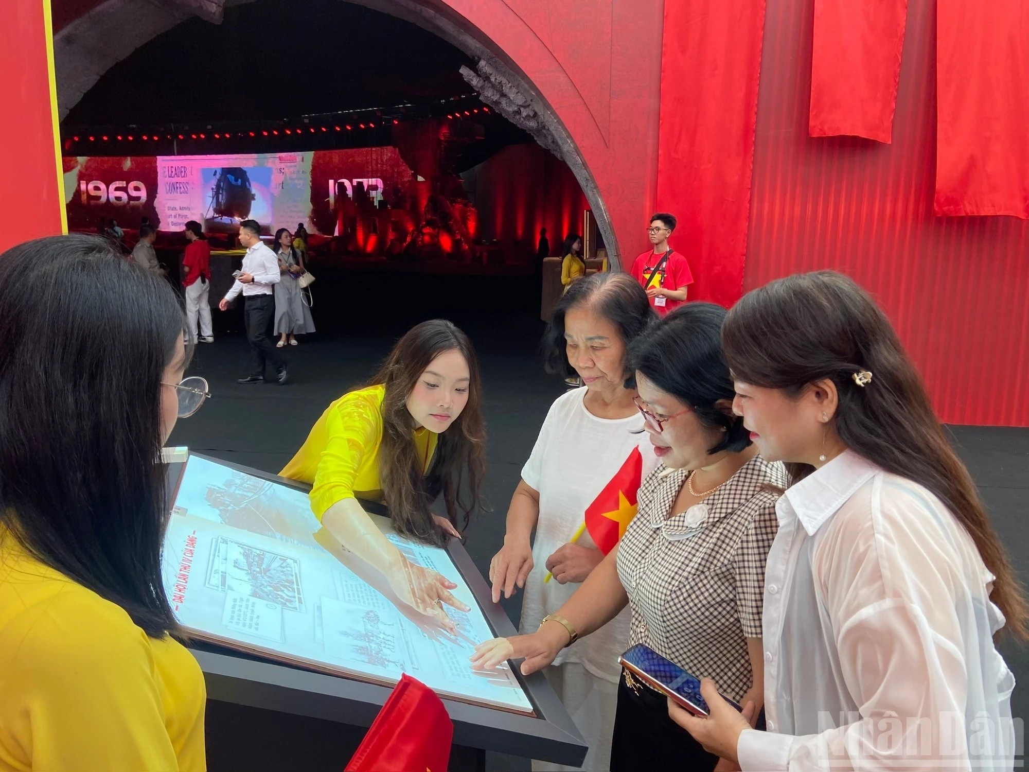 Bà Đỗ Thị Thúy Thân (áo kẻ ô vuông, ở giữa) trải nghiệm thao tác chạm, lướt để khám phá nội dung cuốn sách.