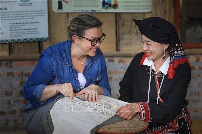 Du khách quốc tế thích thú khi được trải nghiệm công đoạn vẽ họa tiết lên vải thổ cẩm bằng sáp ong.