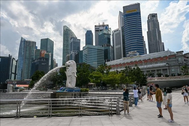 Khách du lịch chụp ảnh bên tượng nhân sư Merlion tại Singapore. Ảnh minh họa: AFP/TTXVN