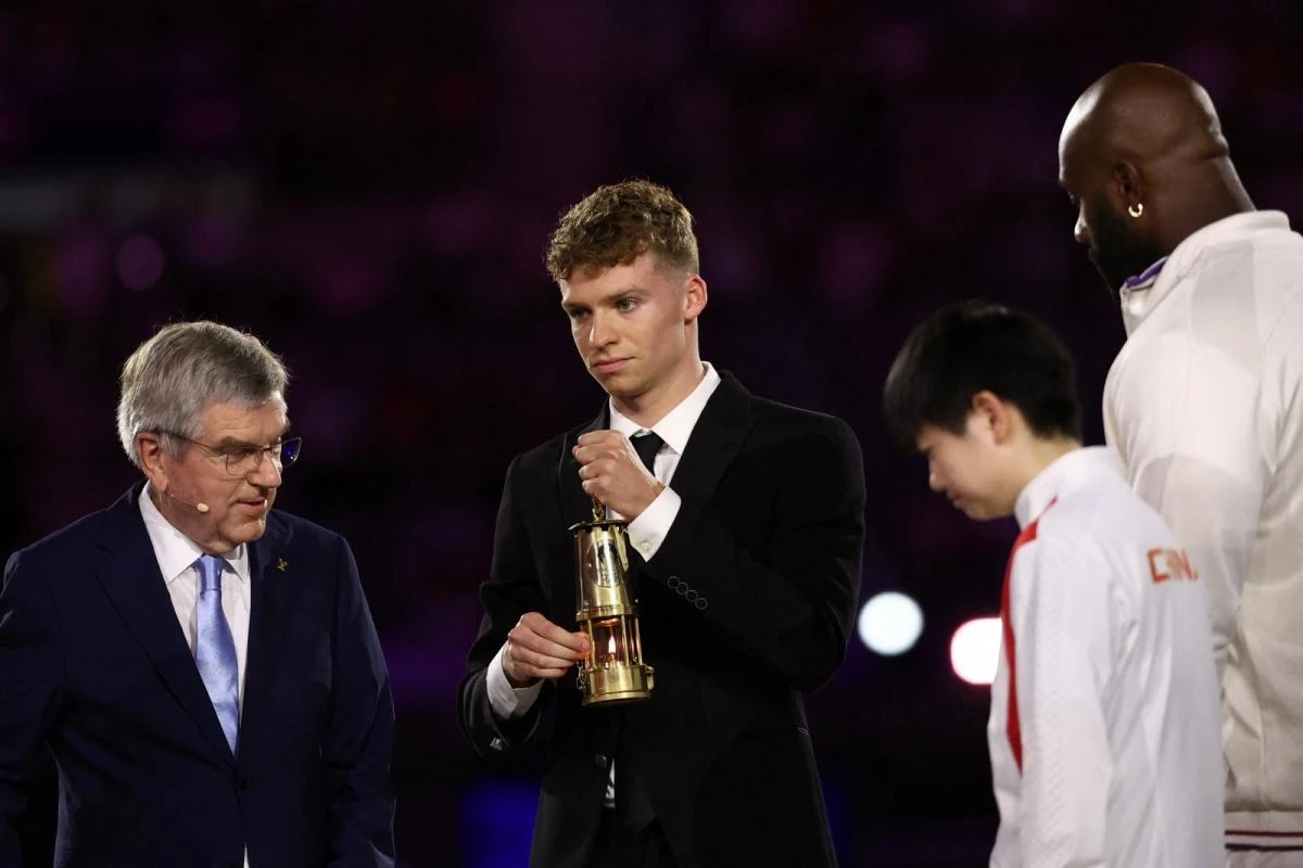 Kình ngư Leson Marchand, người đã đạt nhiều huy chương Vàng tại Thế vận hội Olympic 2024, mang ngọn lửa Olympic đến sân Stade de France. (Ảnh: Le Progrès)