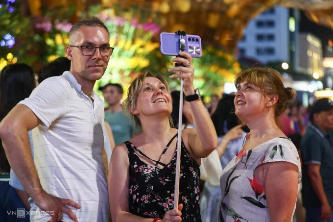 Du khách Ba Lan tham quan đường hoa Nguyễn Huệ tối 29/1. Ảnh: Quỳnh Trần