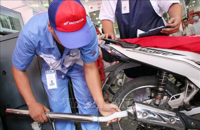 Nhân viên gắn thiết bị kiểm tra khí thải vào ống xả để kiểm tra khí thải. Ảnh tư liệu, minh họa