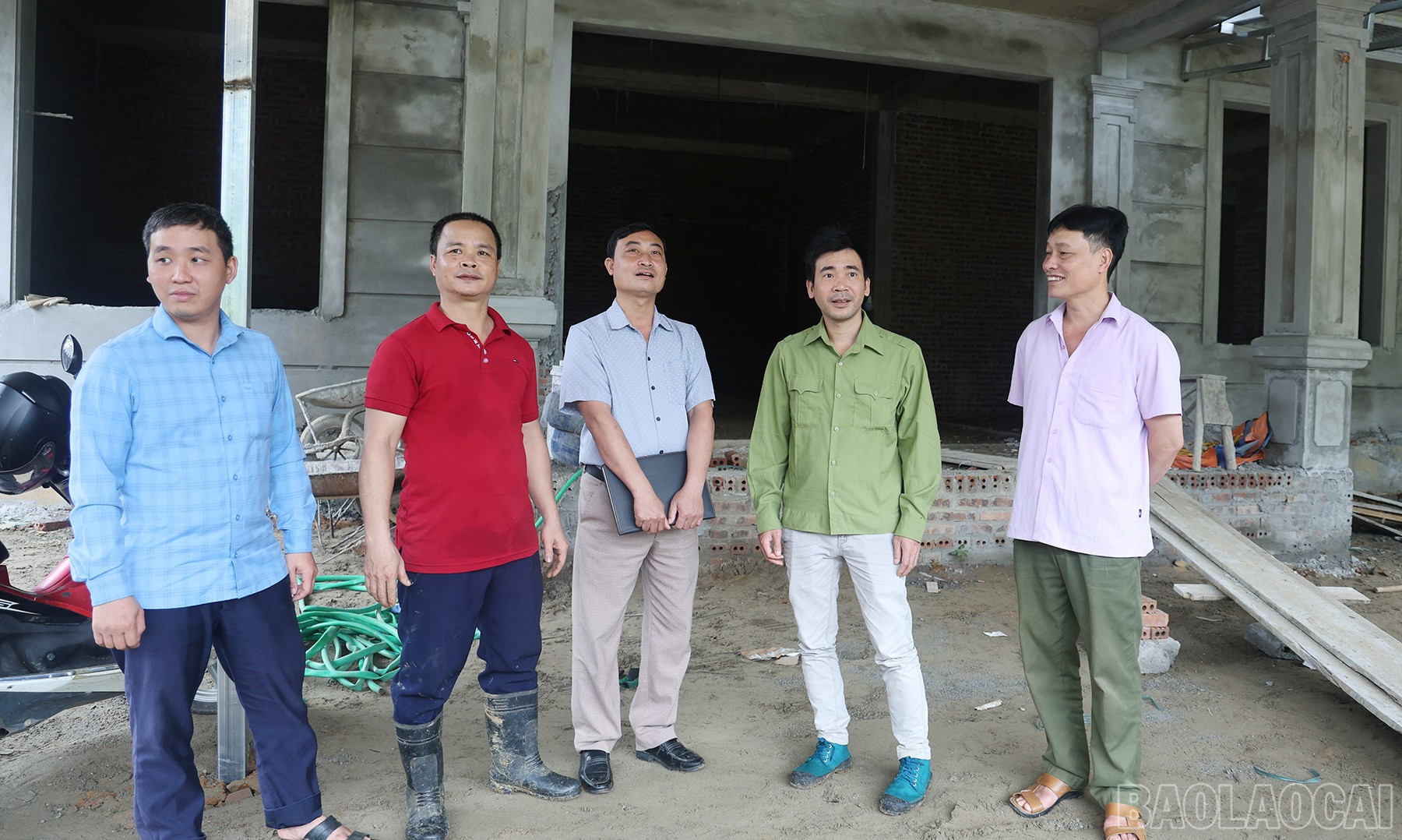 Anh Ngô Văn Bình (ngoài cùng bên phải) bên căn nhà đang trong giai đoạn hoàn thiện thì phải dừng lại do nằm trong phạm vi giải phóng mặt bằng dự án. baolaocai-br_img-0122.jpg