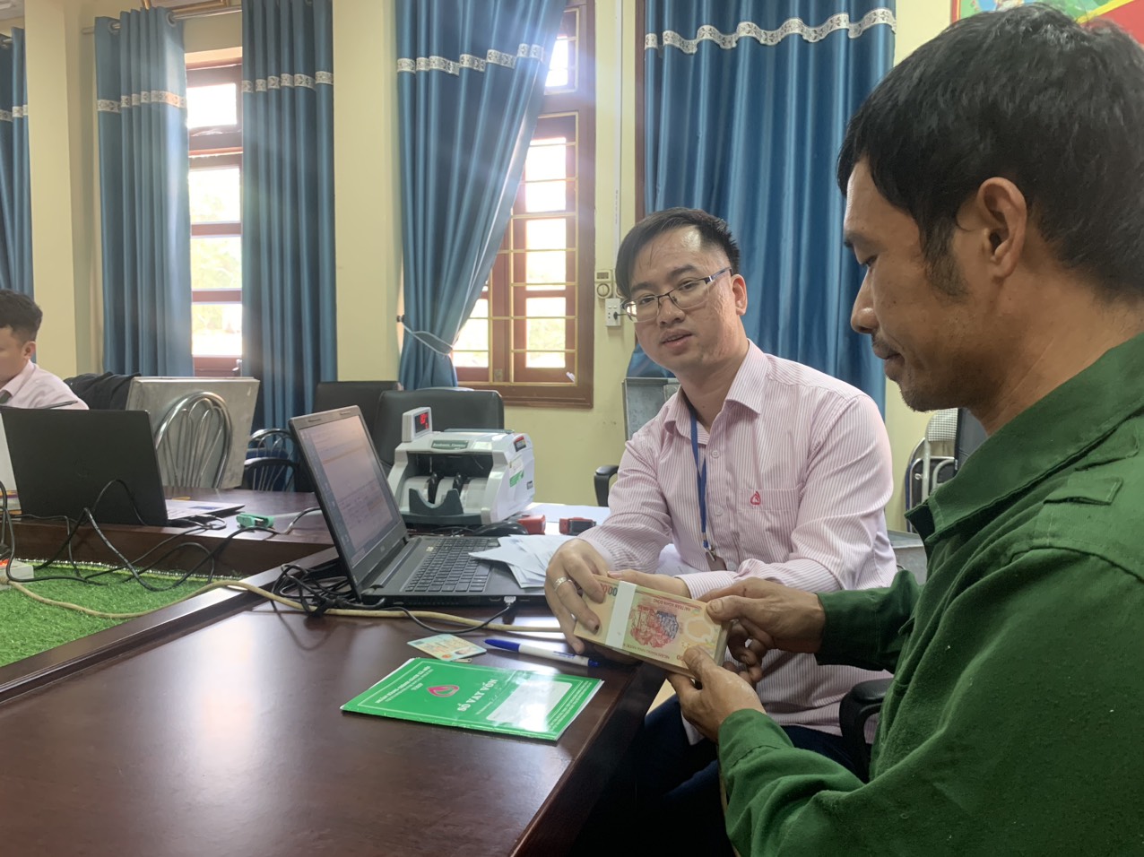 Cán bộ Phòng Giao dịch Ngân hàng Chính sách xã hội huyện Văn Bàn giải ngân vốn cho đối tượng được vay vốn theo chương trình giải quyết việc làm. giai ngan 2.jpg