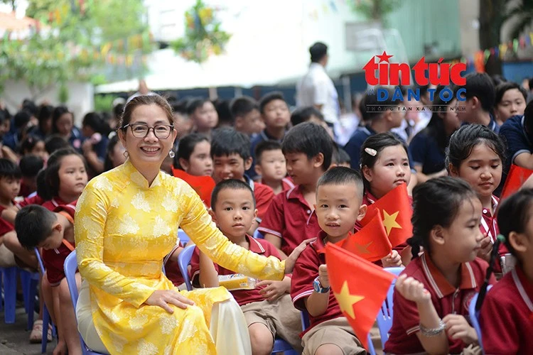 Cô giáo và các em học sinh rạng rỡ trong ngày khai giảng năm học mới, những lá cờ Tổ quốc tạo nên không khí vui tươi, phấn khởi.