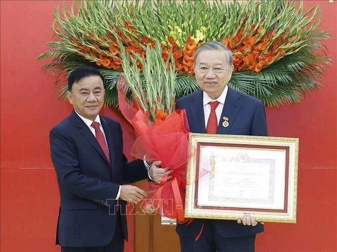 Đồng chí Trần Cẩm Tú, Ủy viên Bộ Chính trị, Thường trực Ban Bí thư trao Huy hiệu Đảng và tặng hoa chúc mừng Tổng Bí thư Tô Lâm.