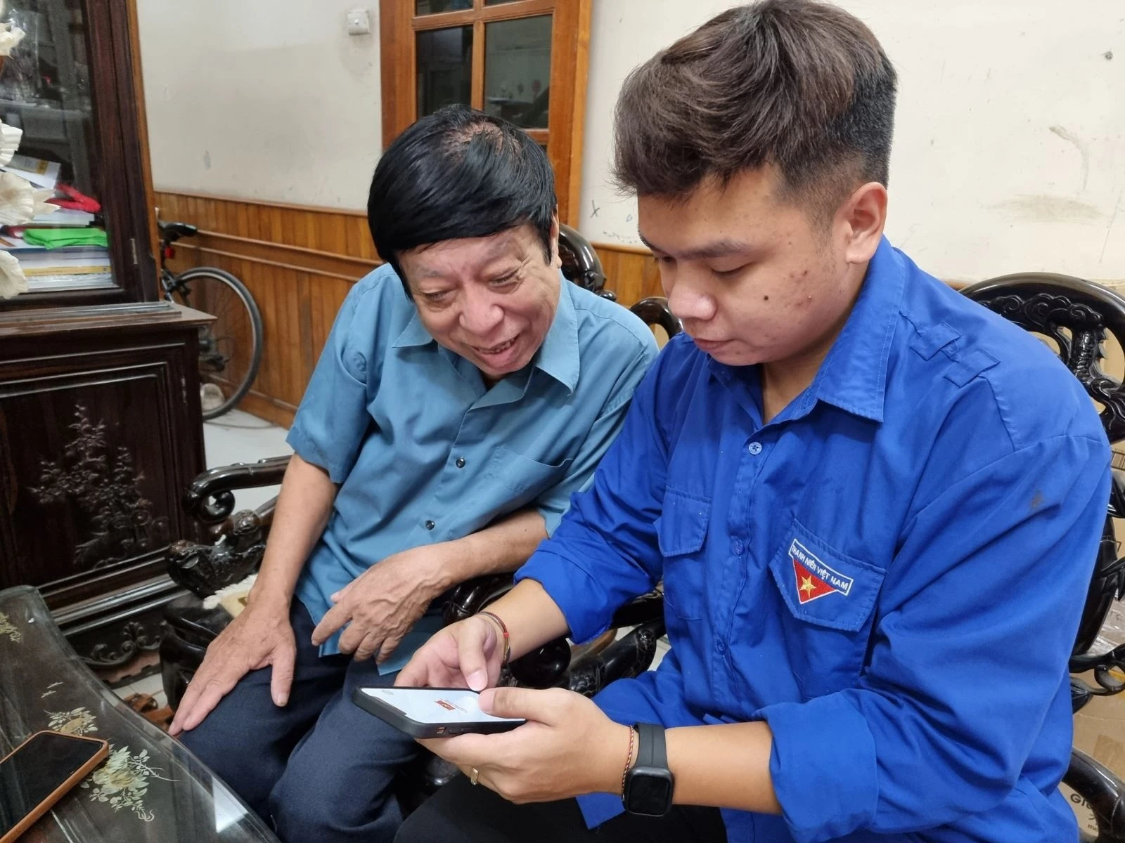Hỗ trợ người cao tuổi kiểm tra tài khoản trên ứng dụng điện thoại di động. Ảnh: XC