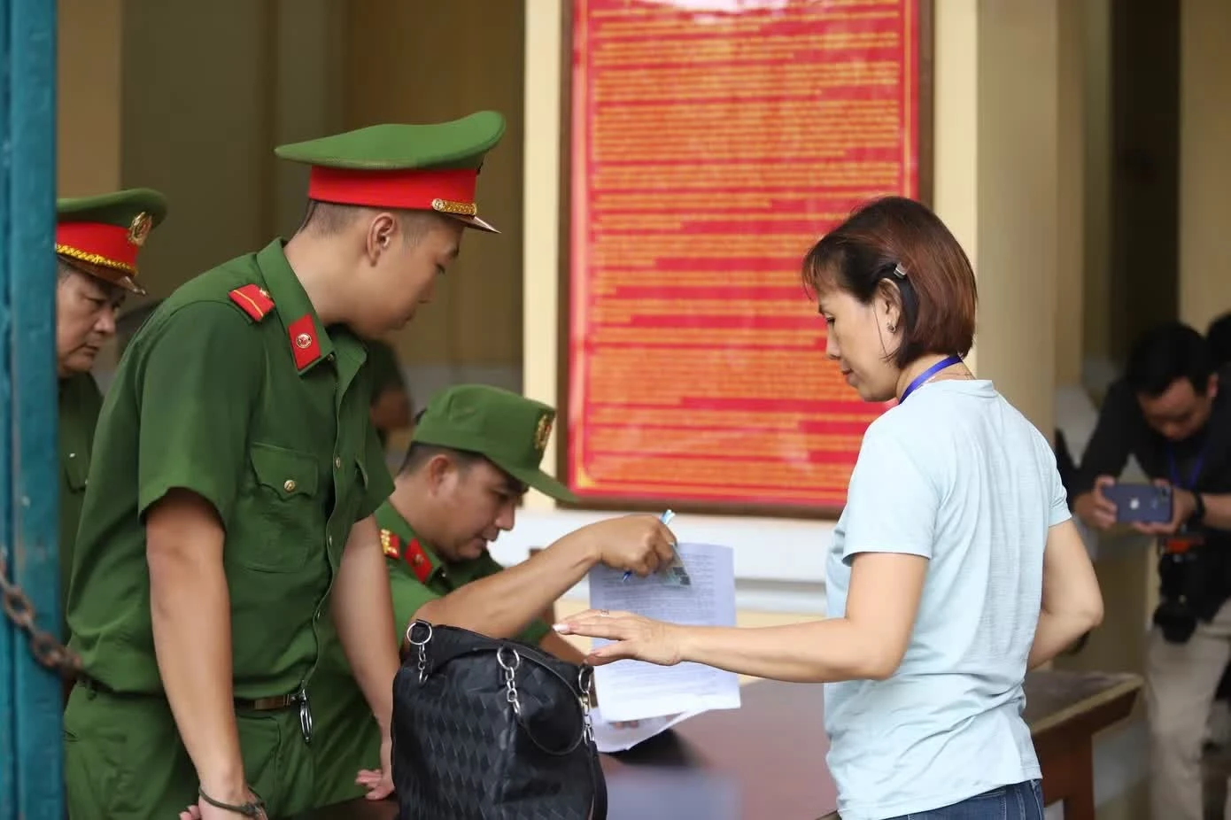 Cảnh sát kiểm tra giấy tờ người vào phòng xử án.