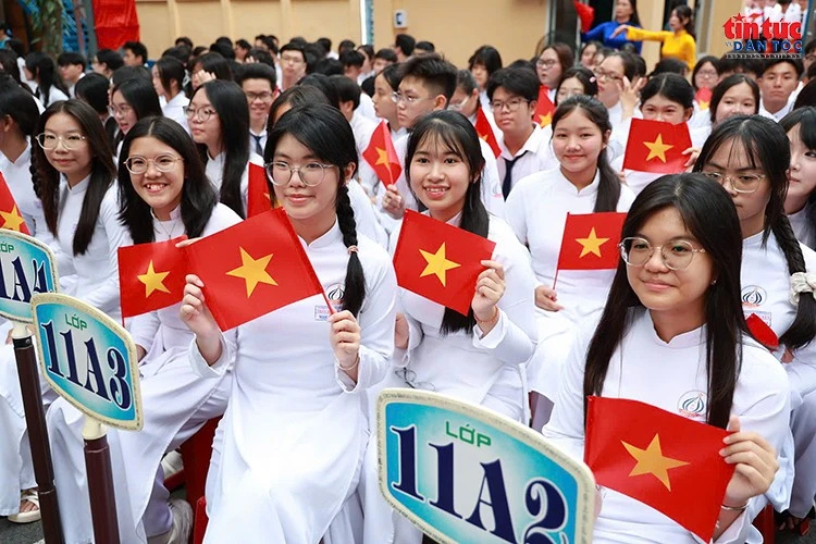 Nữ sinh rạng rỡ trong tà áo dài trắng, tay cầm cờ Tổ quốc, hòa chung không khí vui tươi trong ngày khai giảng năm học 2026–2027.