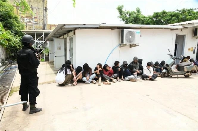 Lực lượng chức năng thuộc Bộ Công an Lào áp giải, quản lý các đối tượng bị bắt giữ trong vụ triệt phá ổ nhóm lừa đảo trực tuyến và cờ bạc qua mạng tại bản Dongphosy, quận Hatxaiphong, thủ đô Viêng Chăn. Ảnh: TTXVN phát