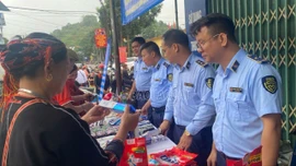 Cán bộ Quản lý thị trường hướng dẫn bà con người Dao xã Khánh Hòa nhận biết hàng thật, hàng giả.