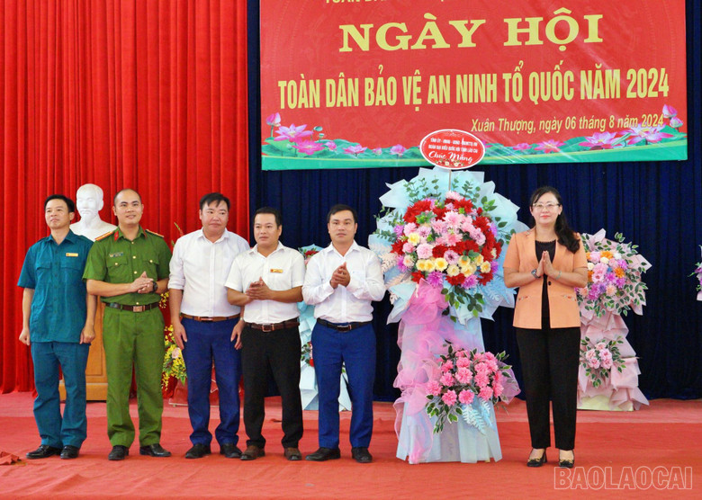 Đồng chí Giàng Thị Dung thay mặt Tỉnh ủy, HĐND, UBND tỉnh tặng hoa chúc mừng Đảng ủy, HĐND, UBND xã Xuân thượng, huyện Bảo Yên.