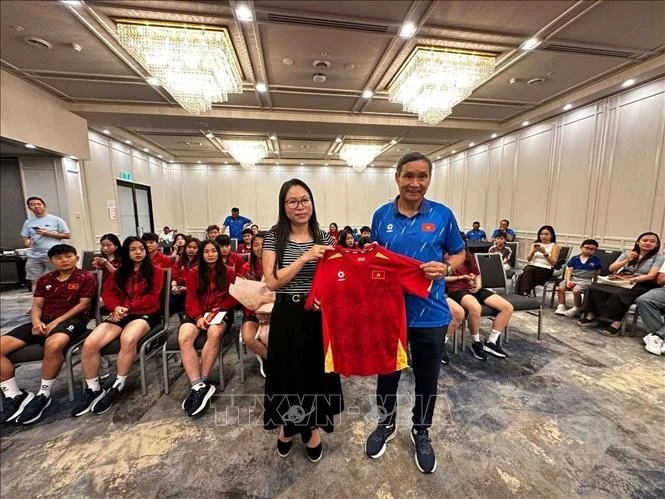 Huấn luyện viên Mai Đức Chung (phải) tặng áo thi đấu có chữ ký của các cầu thủ đội tuyển cho Tổng Lãnh sự Nguyễn Thanh Hà.