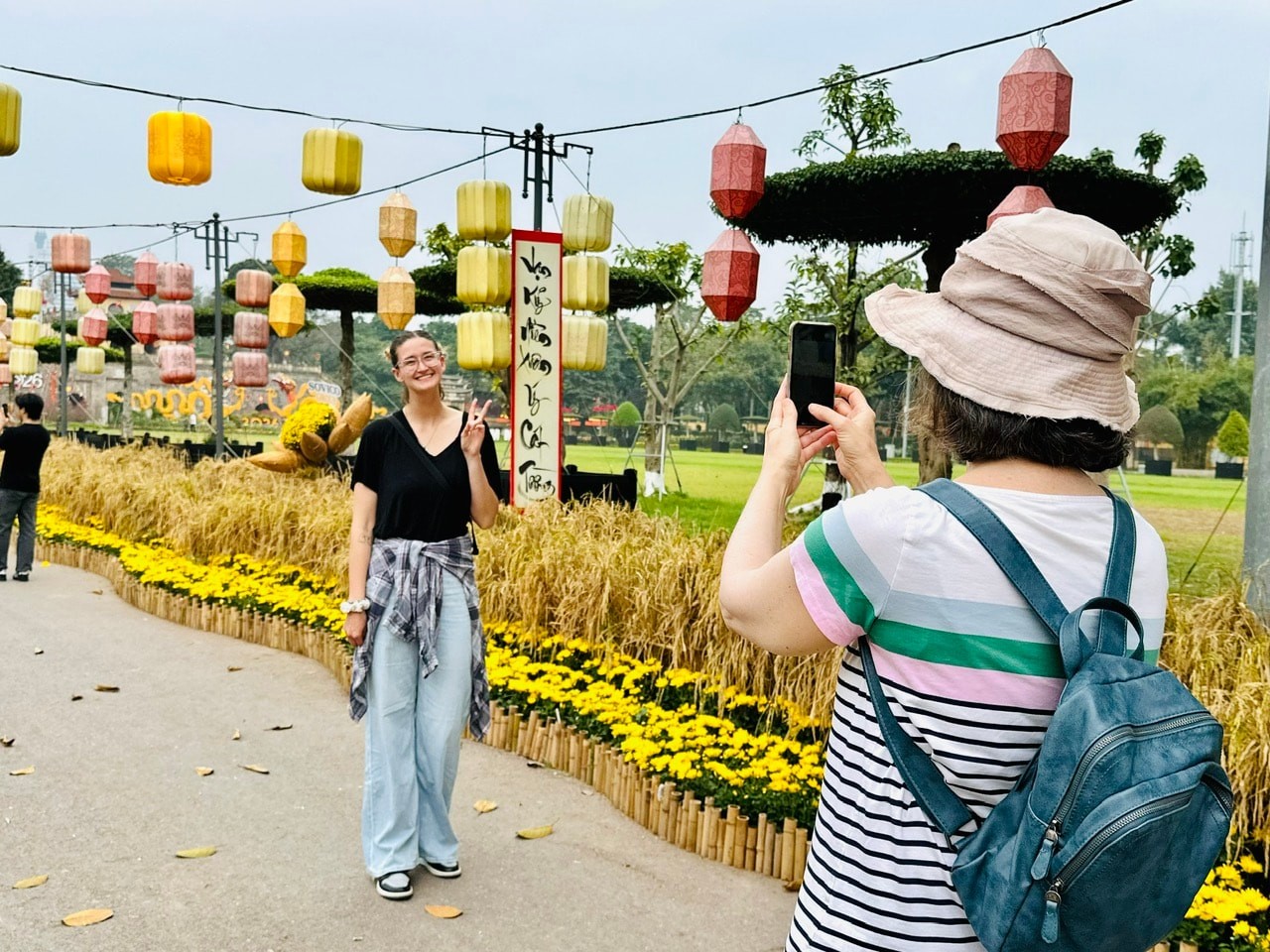 Khách quốc tế thích thú với con đường hoa và lúa chín vàng tại Hoàng thành Thăng Long, Hà Nội vào ngày mùng 1 Tết.
