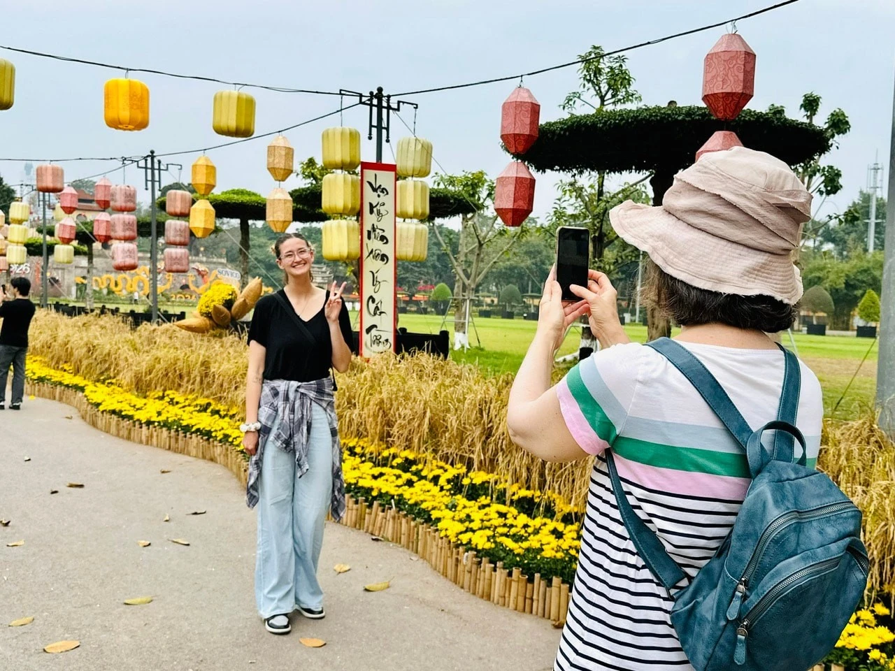 Khách quốc tế thích thú với con đường hoa và lúa chín vàng tại Hoàng thành Thăng Long, Hà Nội vào ngày mùng 1 Tết.