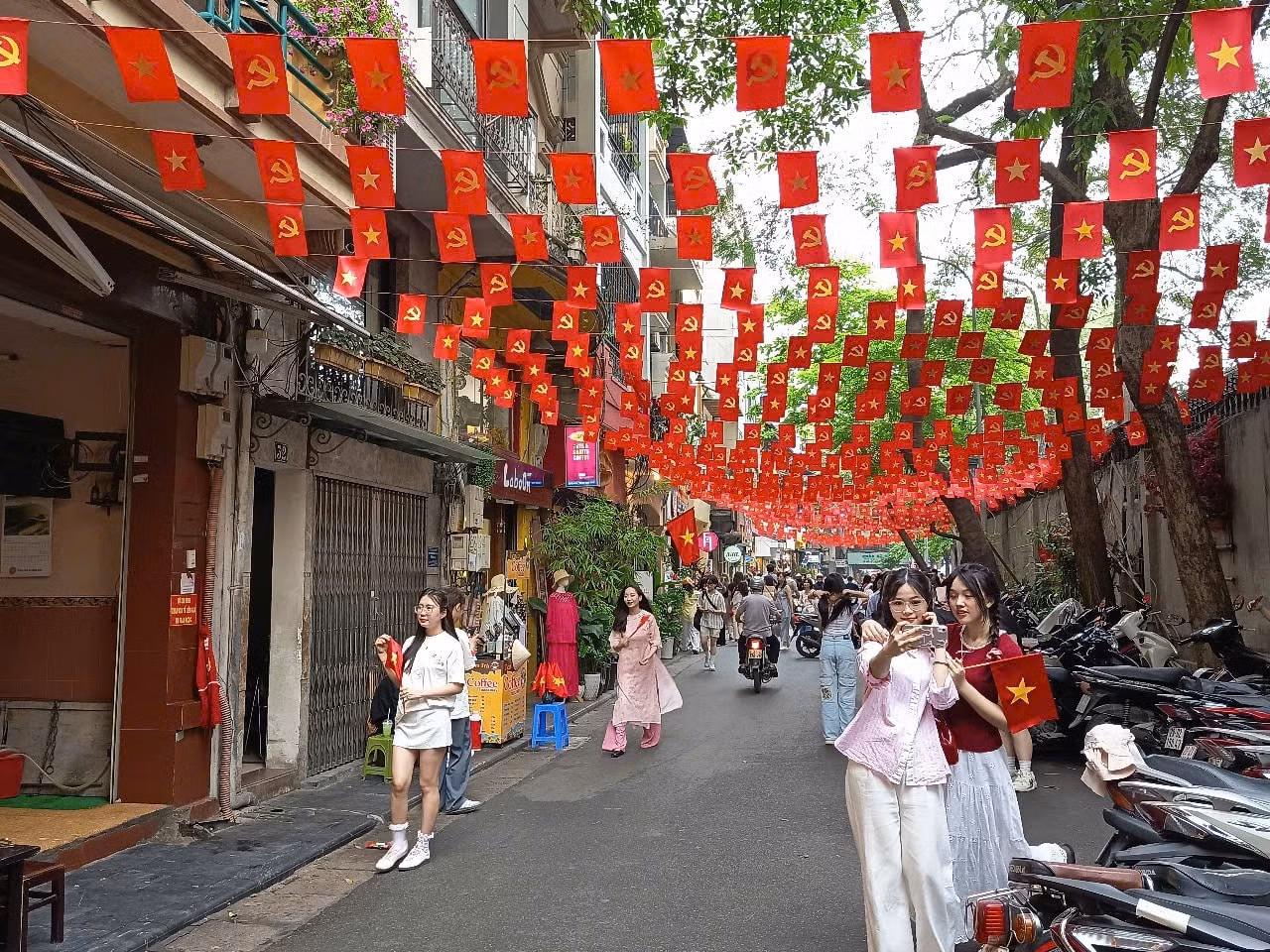 Trên con phố Ấu Triệu (quận Hoàn Kiếm, Hà Nội) thu hút nhiều bạn trẻ đến chụp ảnh dưới lá cờ đỏ sao vàng với niềm tự hào.