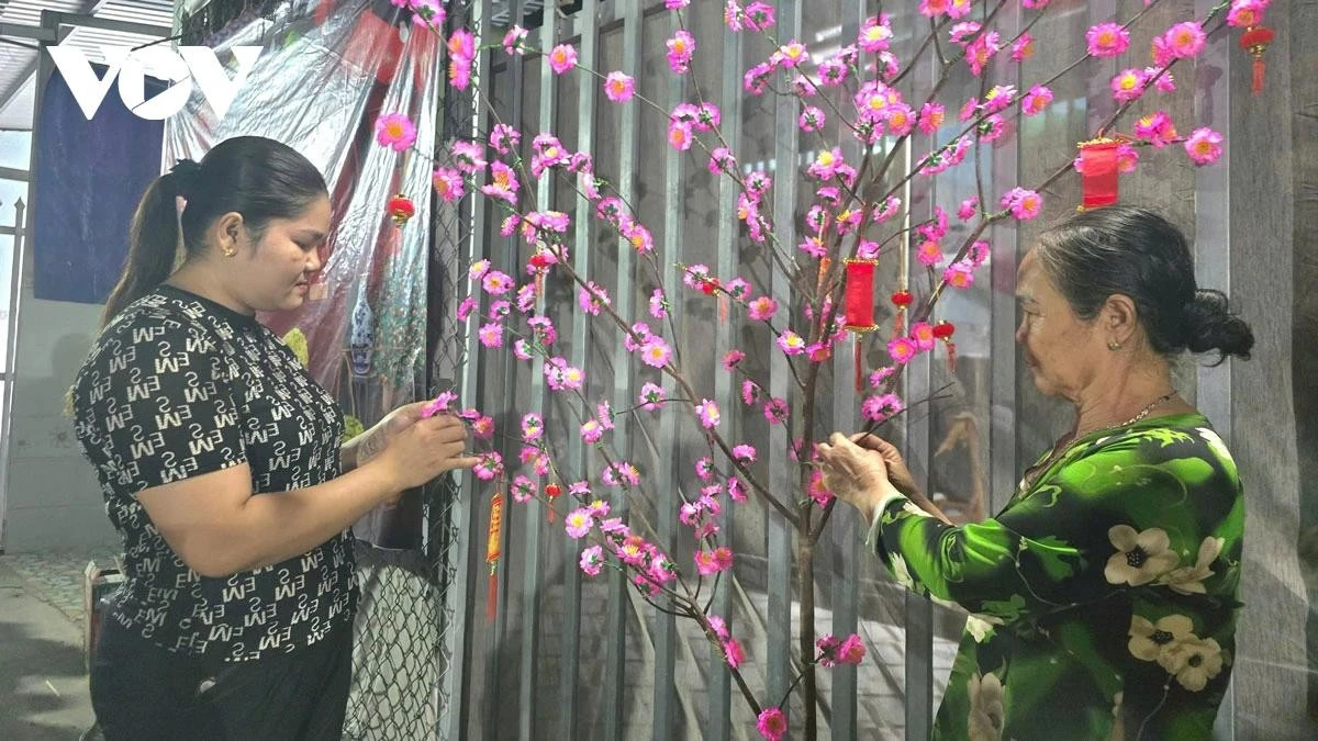 Không được về quê đón Tết, chị Nguyễn Thị Hiền (trái) trang trí cành đào cho căn trọ có thêm sắc xuân.