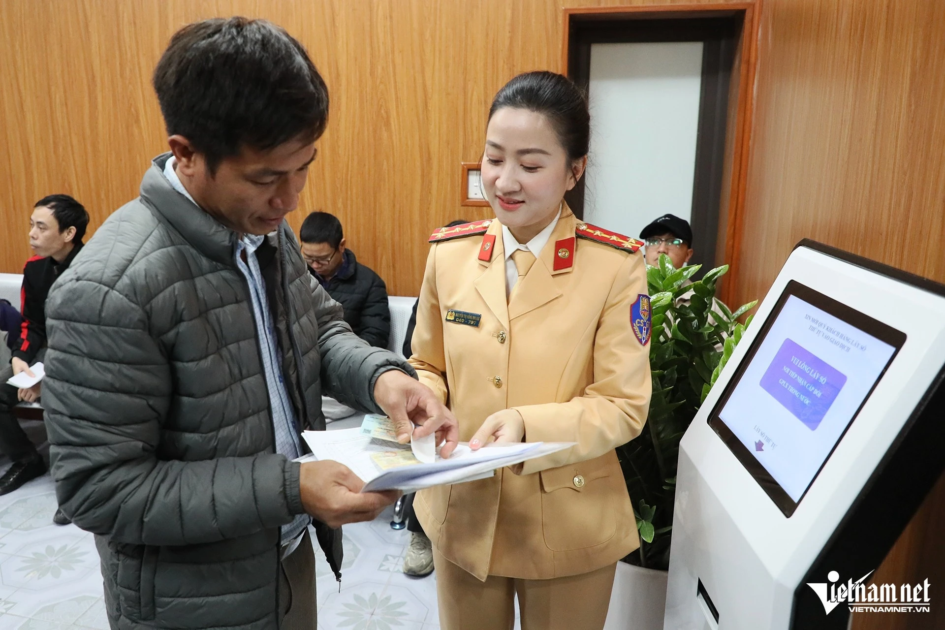 Nữ CSGT hướng dẫn người dân lấy số thứ tự để làm thủ tục cấp đổi giấy phép lái xe.