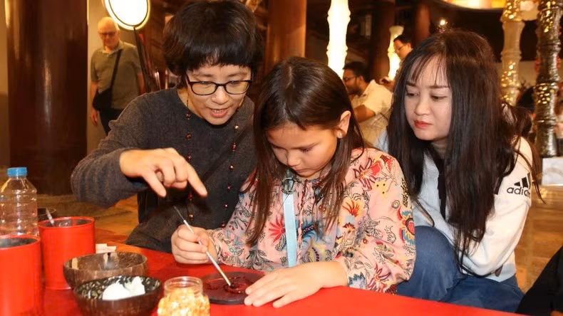 Các nghệ sĩ cùng khách tham quan làm tác phẩm sơn mài tại Văn Miếu - Quốc Tử Giám.