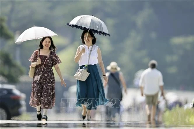 Người dân che ô tránh nắng khi di chuyển trên đường phố ở Tokyo, Nhật Bản. Ảnh: Kyodo/TTXVN