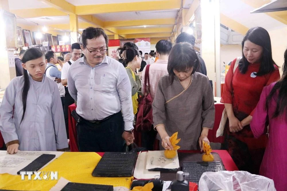Bạn đọc, người tham quan triển lãm có cơ hội trải nghiệm in tranh, kinh Phật trên mộc bản.