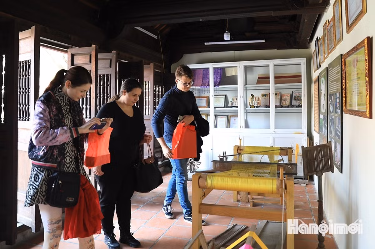 Khách quốc tế tham quan, tìm hiểu sản phẩm tại Nhà truyền thống của làng lụa Vạn Phúc (quận Hà Đông).
