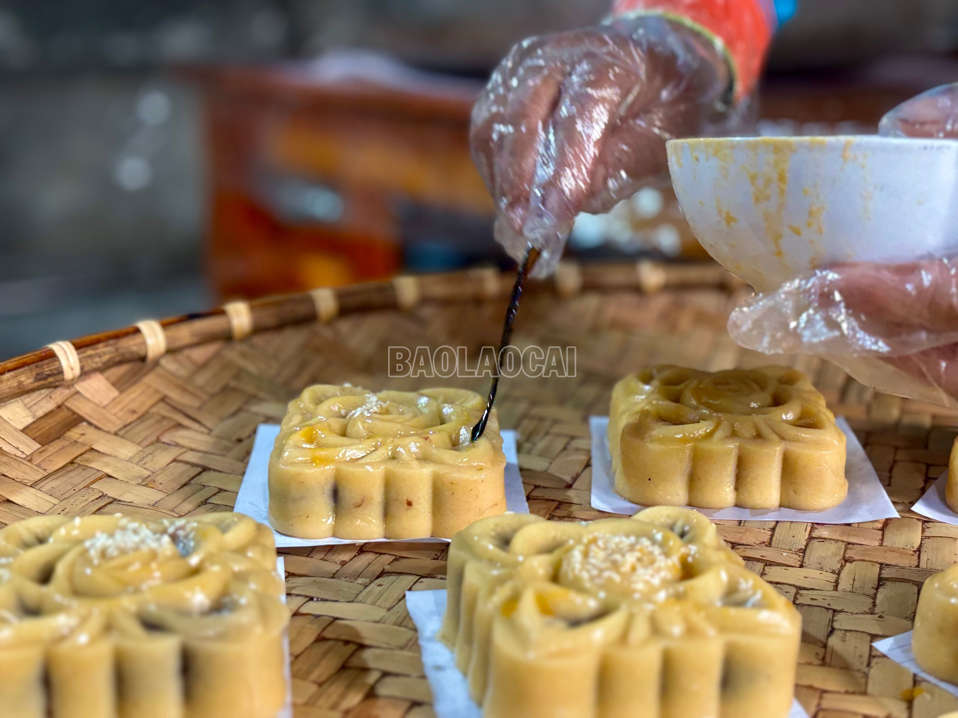 Người phụ nữ Giáy khéo léo phết lớp lòng đỏ trứng lên mặt bánh trước khi nướng – công đoạn đòi hỏi sự tỉ mỉ để bánh khi ra lò có màu vàng đều, dậy hương, hòa quyện cùng vị ngọt bùi đặc trưng. baolaocai-c_img-1324.jpg