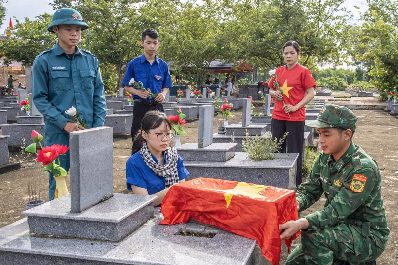 Các đoàn viên thanh niên kính cẩn nghiêng mình trước khi quan tài được chôn cất trở lại. (Ảnh: Lê Văn Chương)