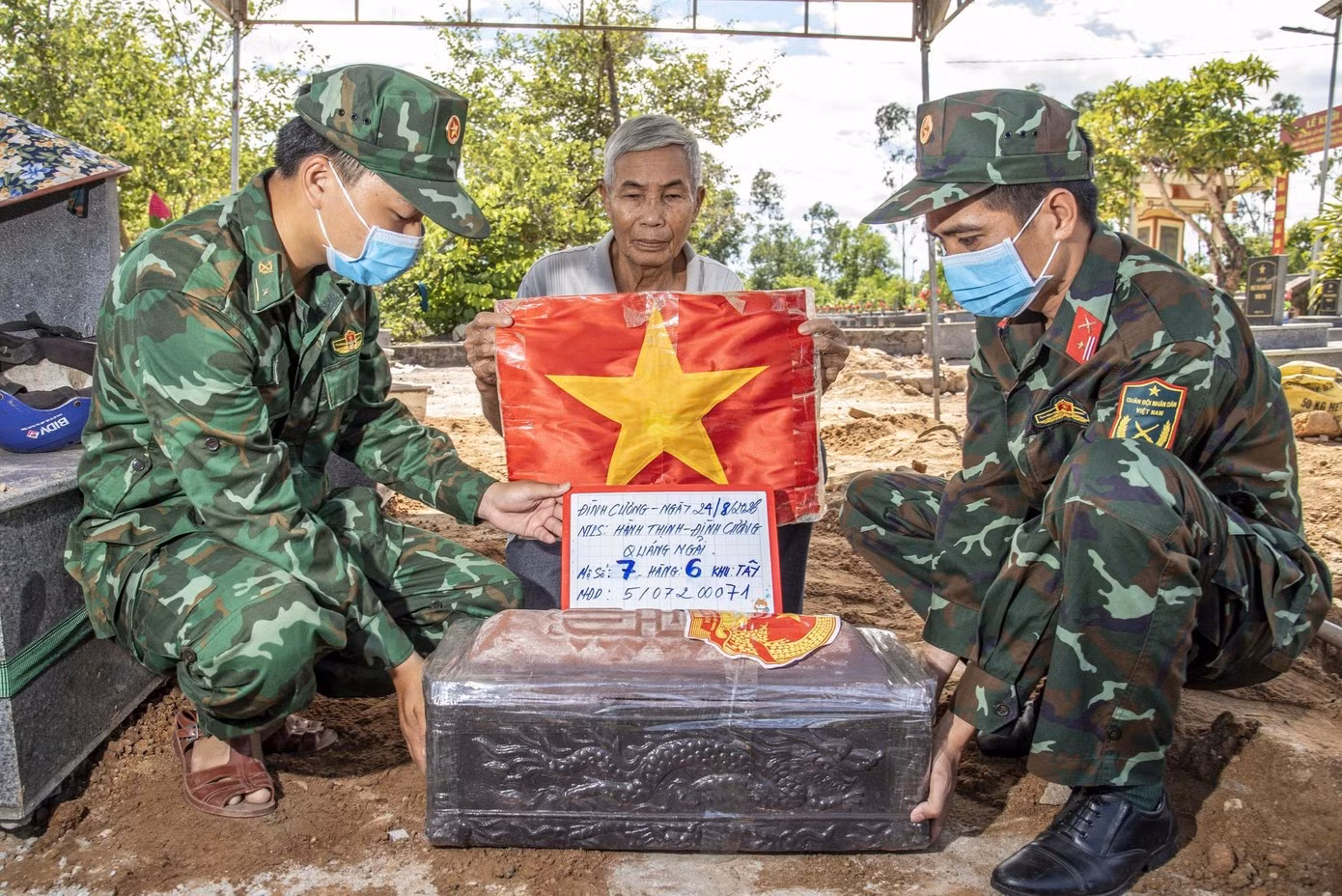 Trên chiếc quan tài được chôn cất trở lại có dán hình Quốc huy, chụp ảnh lưu lại định danh. (Ảnh: Lê Văn Chương)