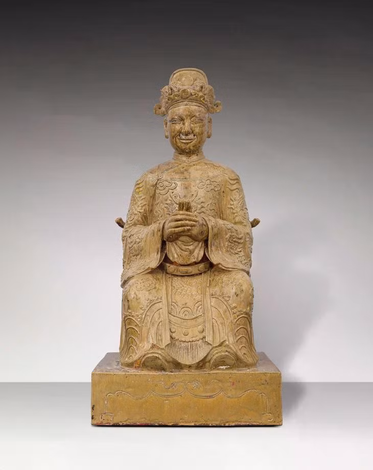 Tượng Thiên quan Đại đế trong tư thế ngồi trên ngai, đặt trên bệ hình chữ nhật. Đầu đội mũ phốc tròn đắp nổi “lưỡng long chầu ngọc”. Khuôn mặt phúc hậu, miệng hơi mỉm cười, hai tai to, trên mặt tạo 5 lỗ để gắn râu. Thân mặc áo long bào lập lĩnh, hình rồng 4 móng và mây đắp nổi trên thân áo, rồng trước ngực nhìn chính diện, ống tay áo rộng, có đai. Hai tay chắp trước ngực, bàn tay trái bên trong, bàn tay phải bên ngoài, hai ngón cái dựng đứng chạm vào nhau (nhất chỉ kình thiên), chân mang hia. Lưng tượng có lỗ vuông - nơi đặt những vật phẩm trong nghi lễ được gọi là “Yểm tâm tượng”.